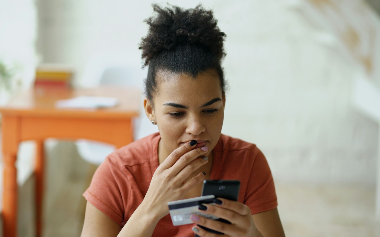 Do banks refund scammed money? A worried woman checking her bank card and phone after a scam